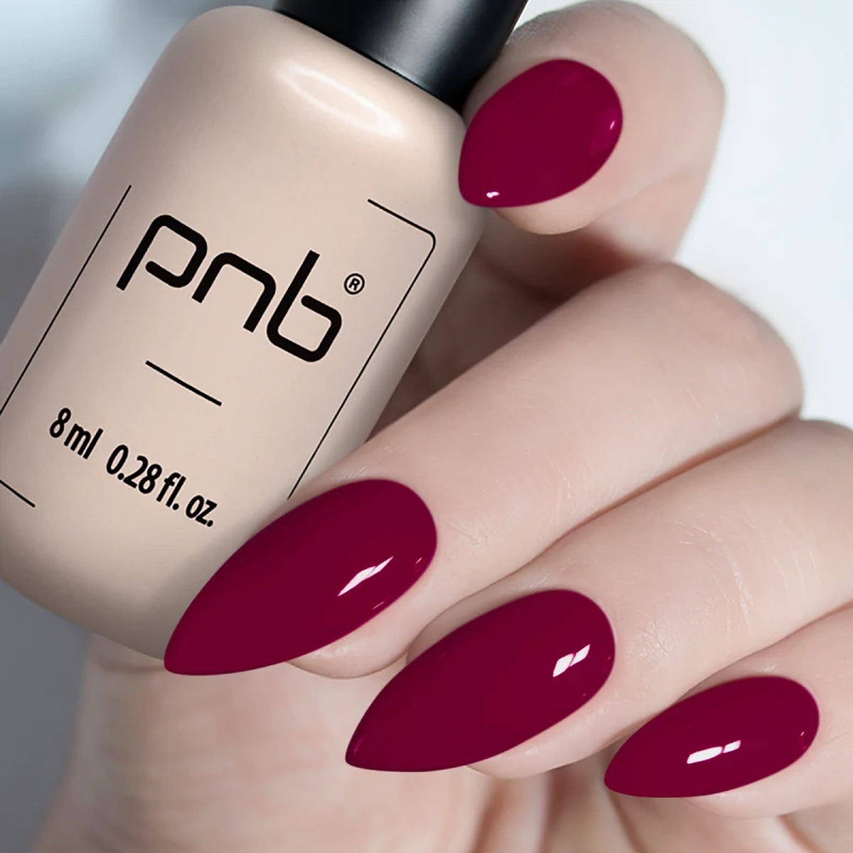 manucure gel rubis de pnb, Vernis gel PNB 8 ml tenu en main, avec des ongles en amande vernis d’un rouge bordeaux brillant, manucure professionnelle UV/LED