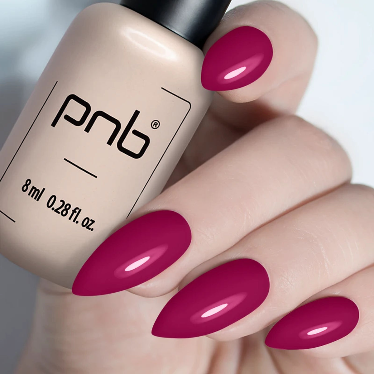 Vernis gel PNB 8 ml tenu en main, avec des ongles en amande vernis d’un rose framboise brillant, manucure professionnelle UV/LED